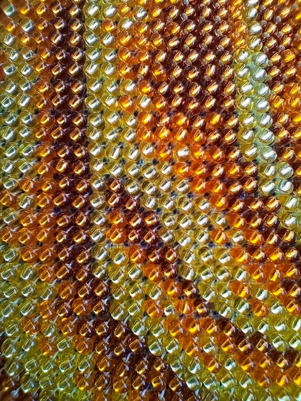 Extreme macro photograph of individually stitched glass beads in amber, gold and pale yellow on the Gold Madonna artwork.