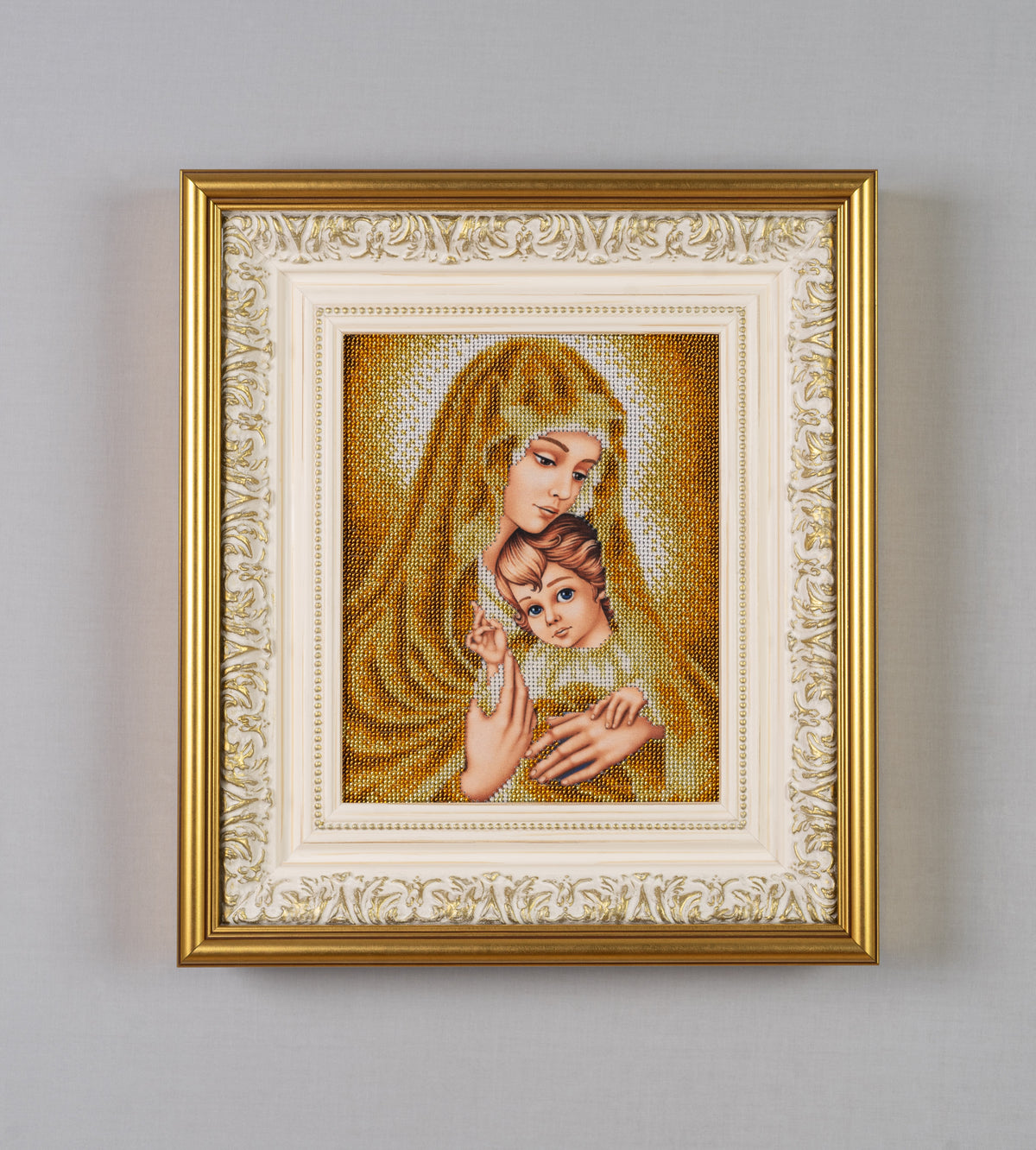 Frontal view of Gold Madonna bead embroidery artwork showing the Virgin Mary and Child surrounded by a decorative ivory-and-gold frame.