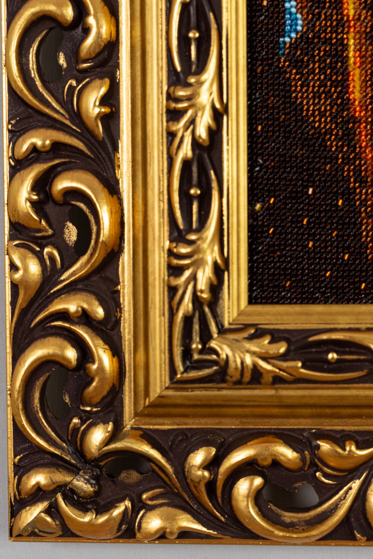 Close-up of the ornate Injac wooden frame with gold-leaf finish surrounding the Madonna bead embroidery