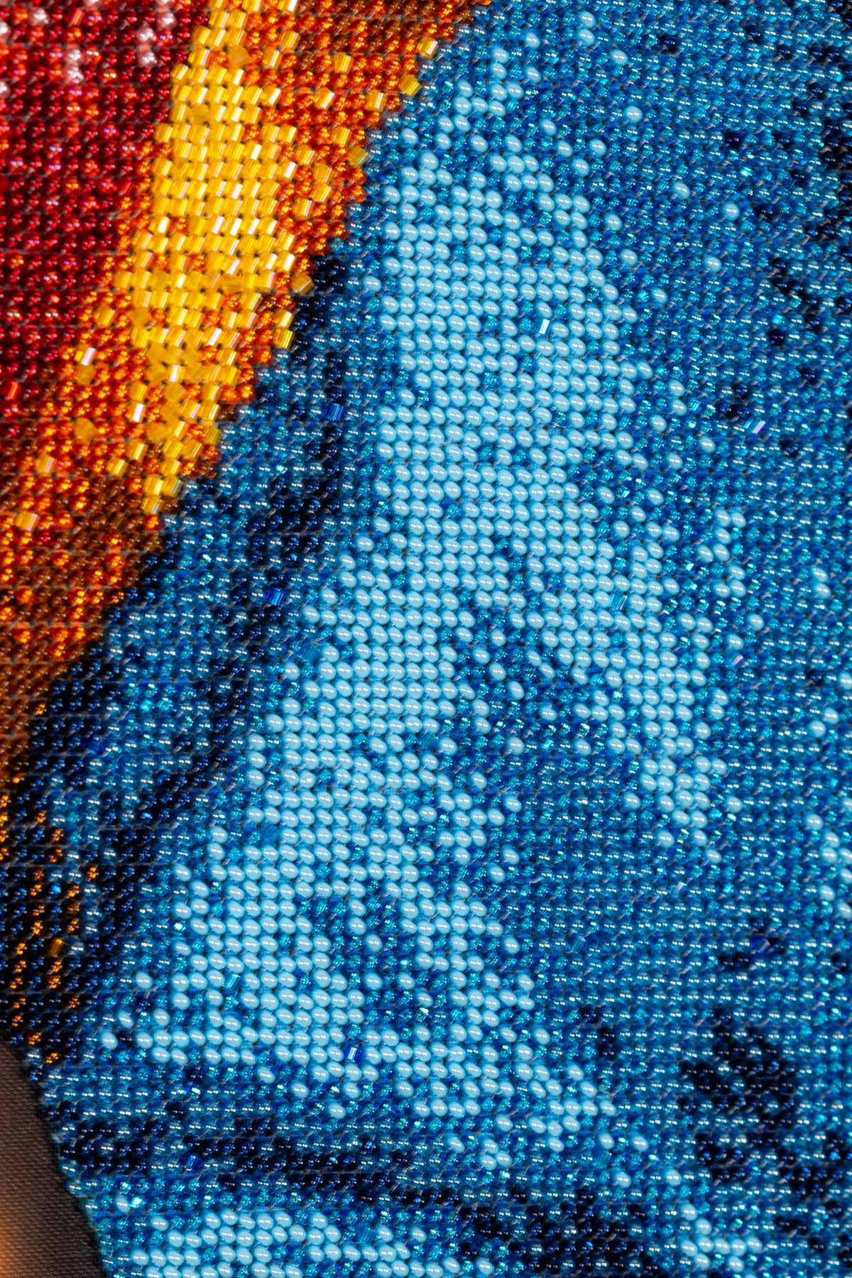 Macro detail of blue Czech seed bead embroidery showing the dense hand-stitched texture and colour variations