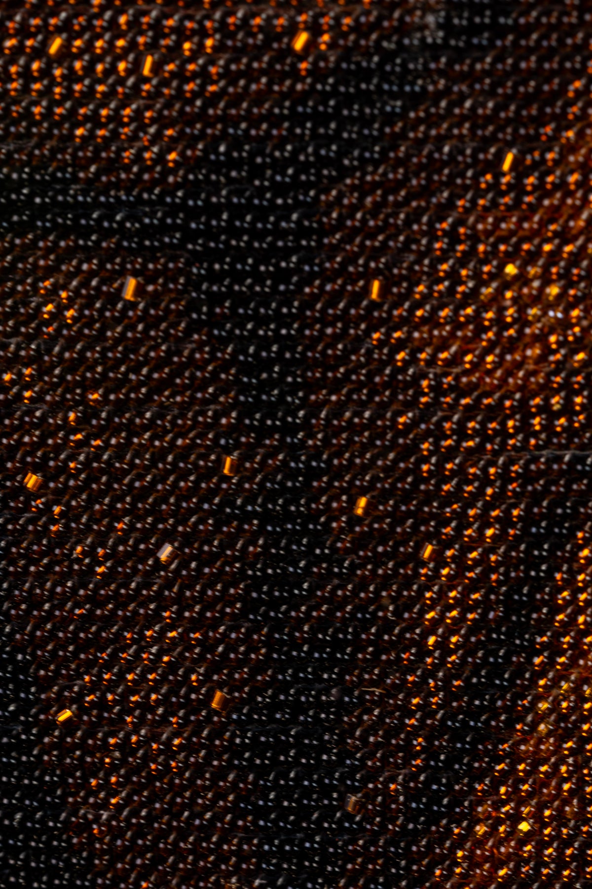 Macro detail of dark brown and black bead embroidery with warm bronze highlights in St. Joseph & Jesus