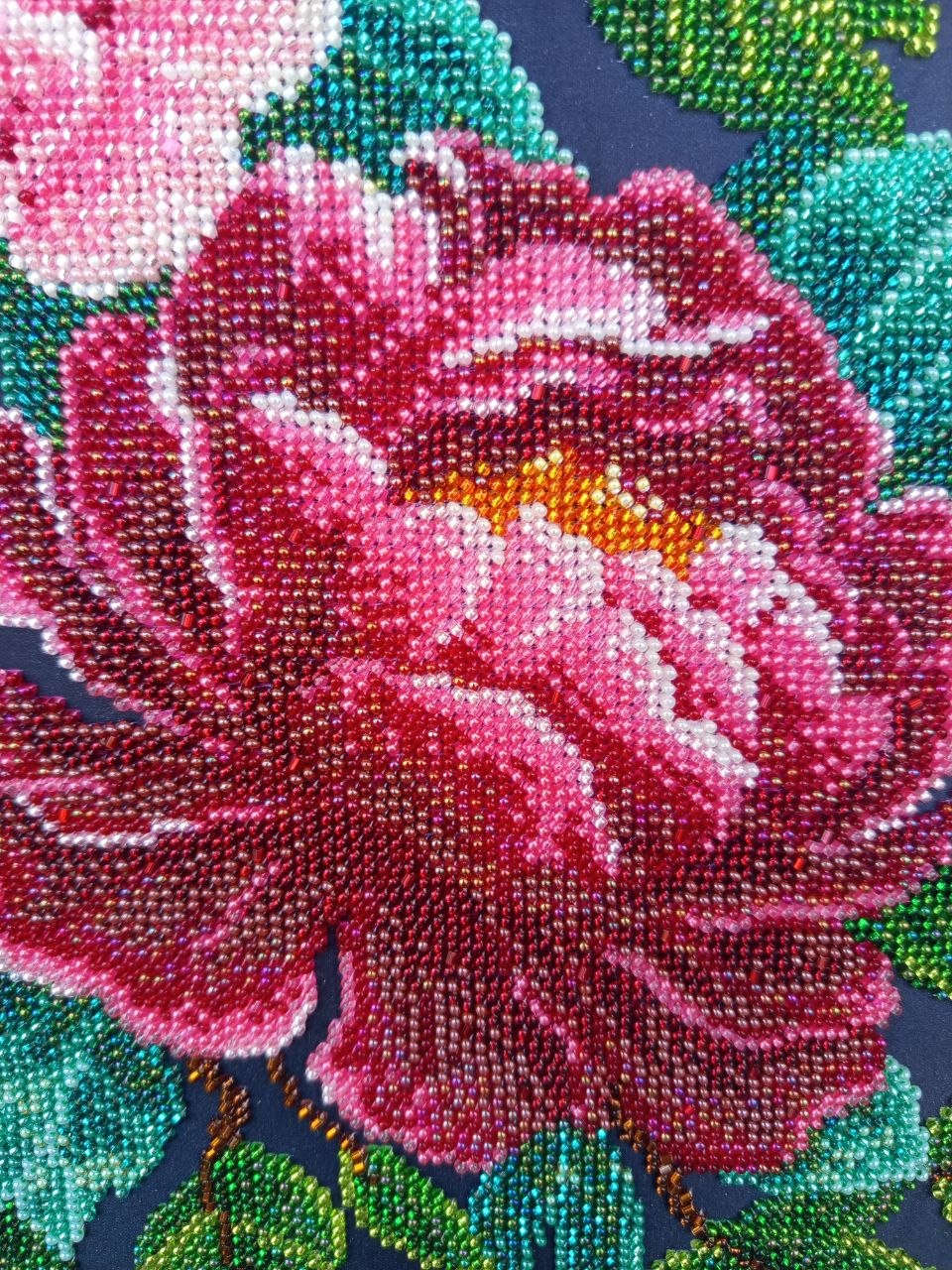 Macro detail of a deep crimson peony created with layered red, pink and amber glass beads