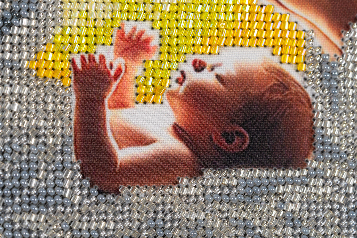 Close-up of the infant Jesus in Incarnation, showing detailed bead embroidery in the Nativity composition