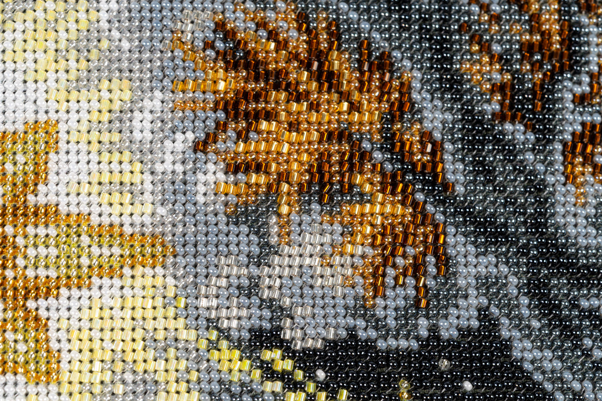 Macro detail of dark grey, black and amber bead embroidery in the upper section of Incarnation