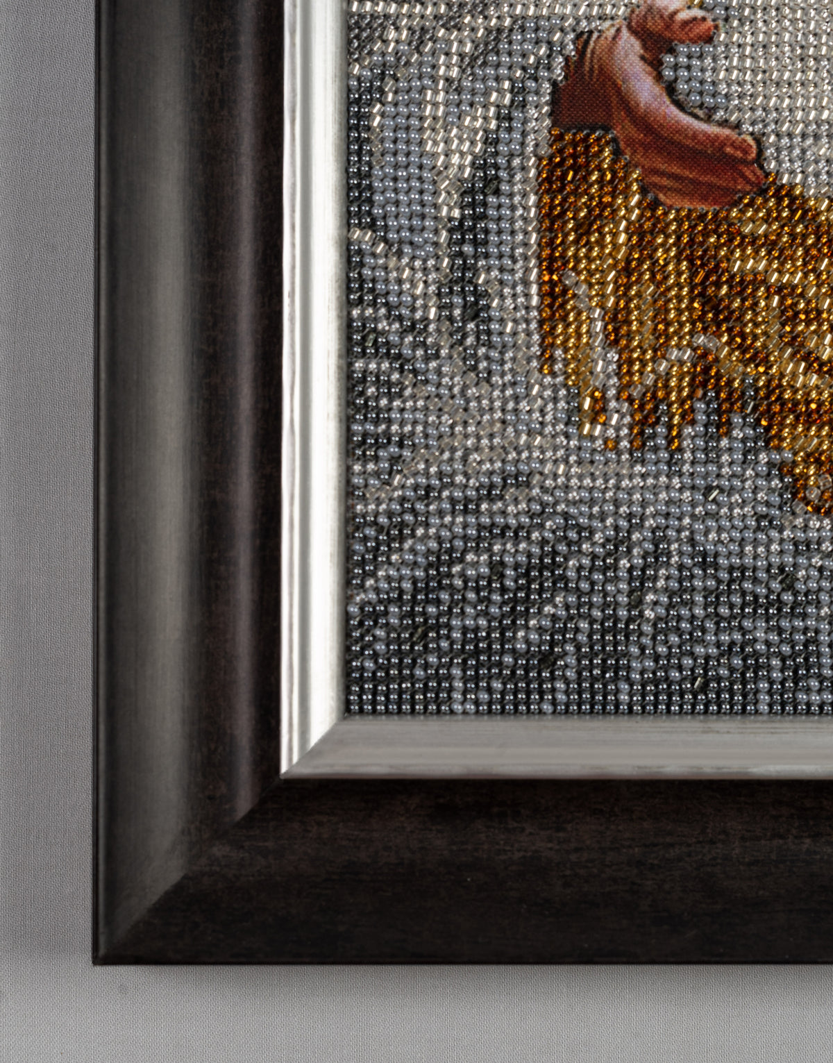 Frame detail of Incarnation showing the dark wooden frame with silver inner accent and bead embroidery