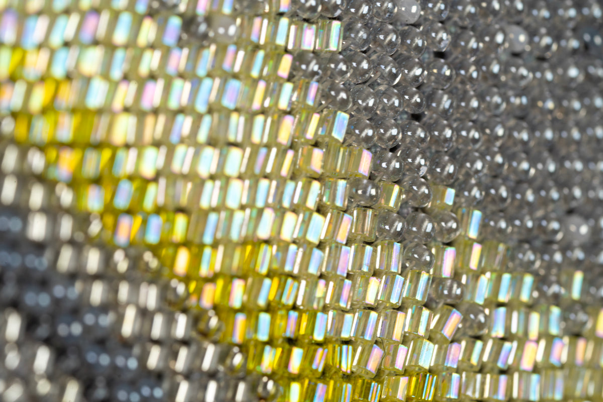 Macro detail of gold, silver and grey bead embroidery in Incarnation, showing variations in bead shape and finish