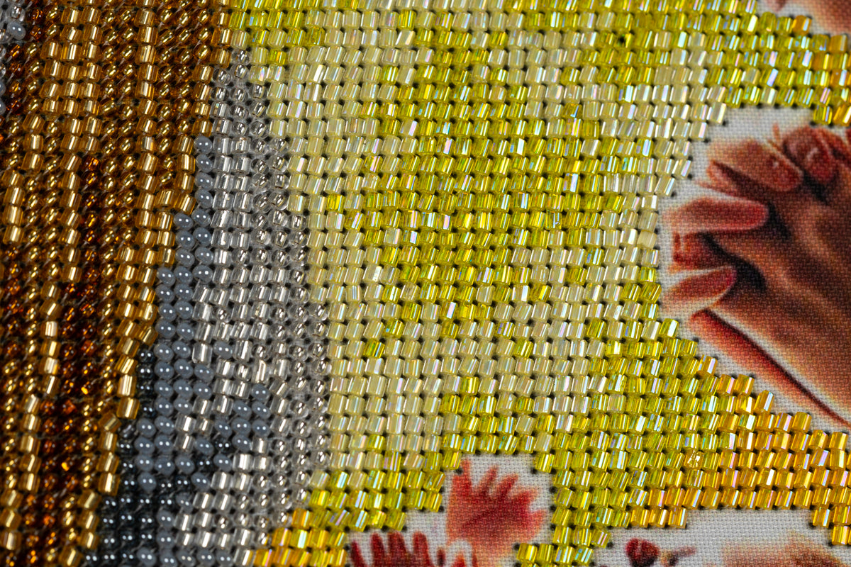 Close-up of luminous yellow, silver and grey bead embroidery surrounding the infant Jesus in Incarnation