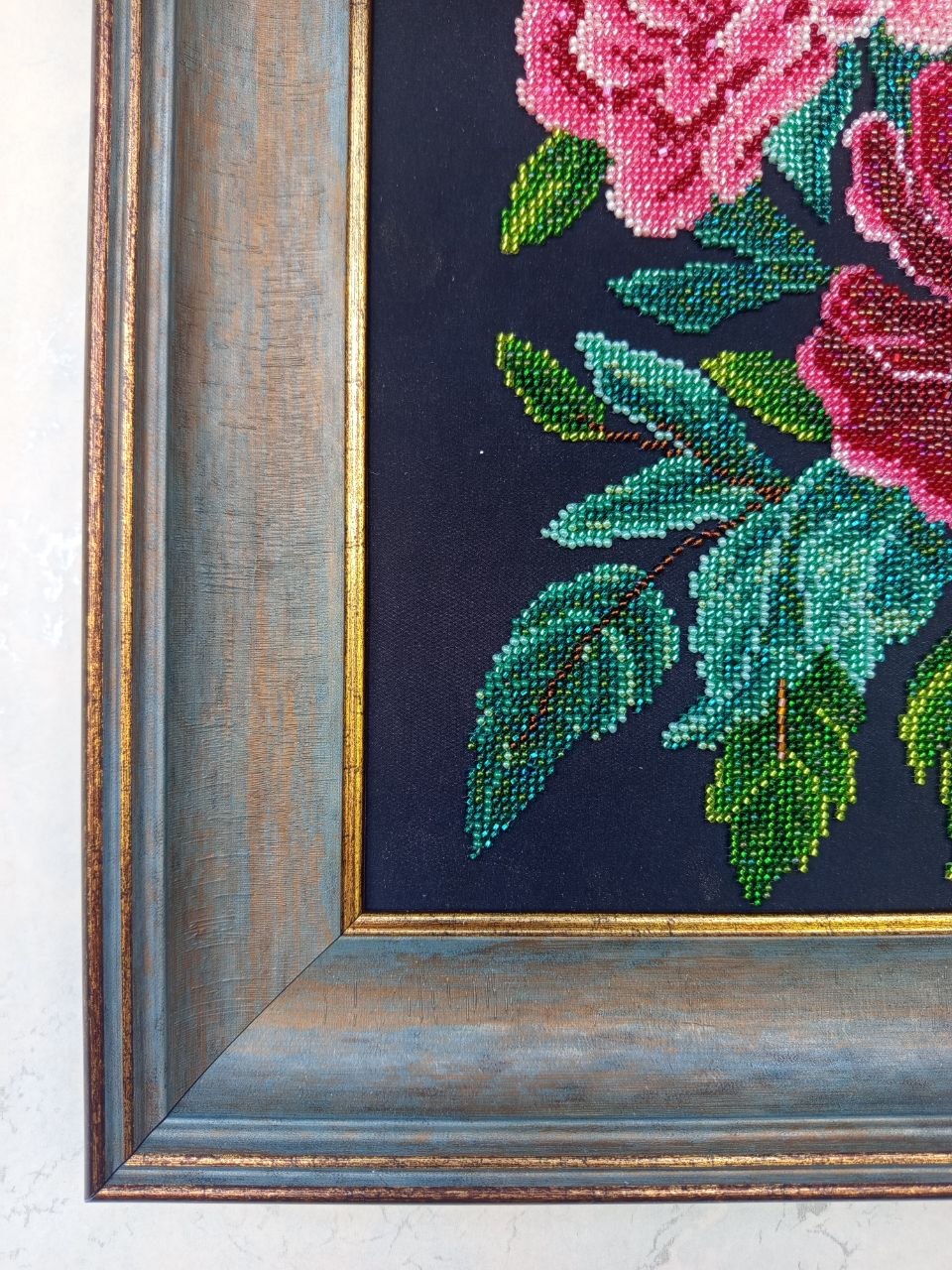 Close-up side view of the decorative blue-grey and bronze frame surrounding Peonies in Bloom bead embroidery