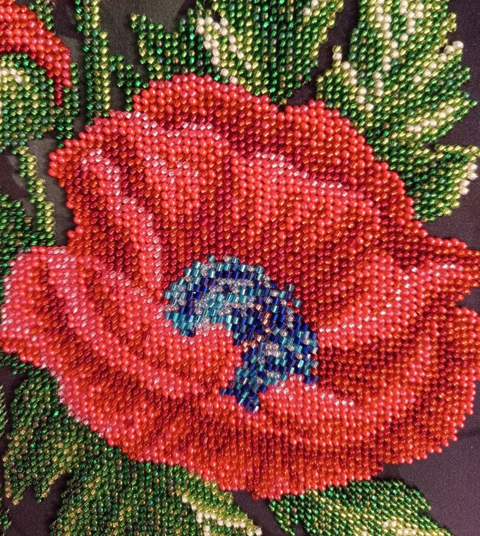 Close-up of a red poppy flower showing layered beadwork and a contrasting blue centre