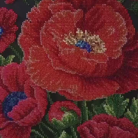 Close-up video of Poppies of Memory, an original hand-embroidered bead artwork. The camera moves across vibrant red poppy petals, revealing intricate glass beadwork, dimensional textures, and shimmering details in the flower centers.