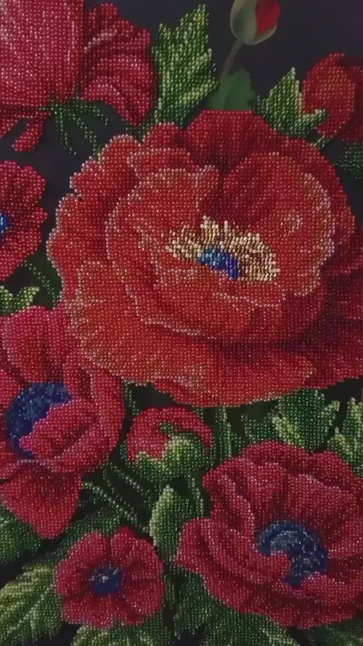 Close-up video of Poppies of Memory, an original hand-embroidered bead artwork. The camera moves across vibrant red poppy petals, revealing intricate glass beadwork, dimensional textures, and shimmering details in the flower centers.