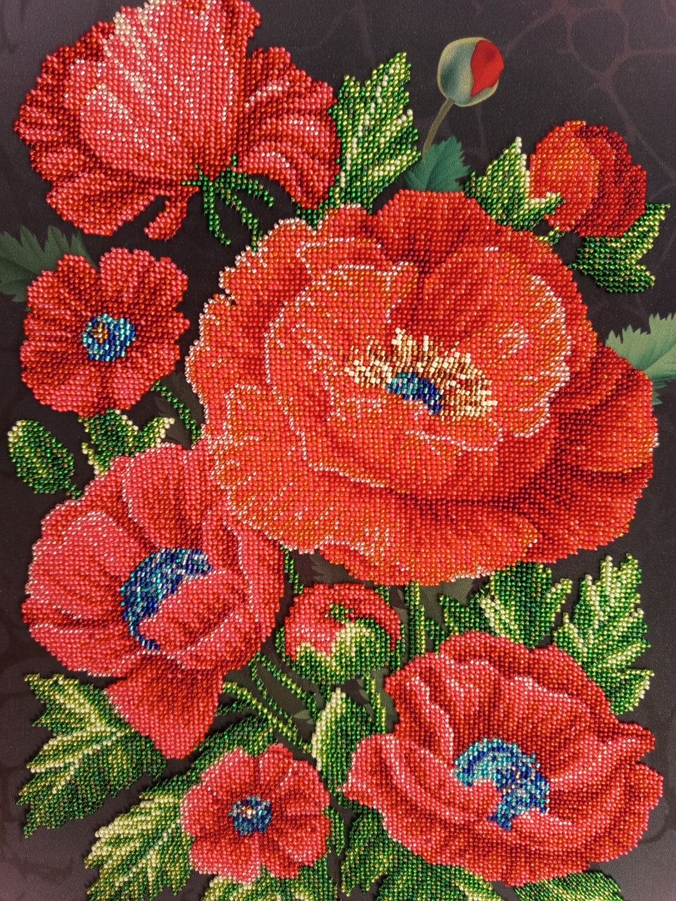 Close-up of Scarlet Poppies showing red flowers, green leaves and detailed hand-applied glass bead embroidery
