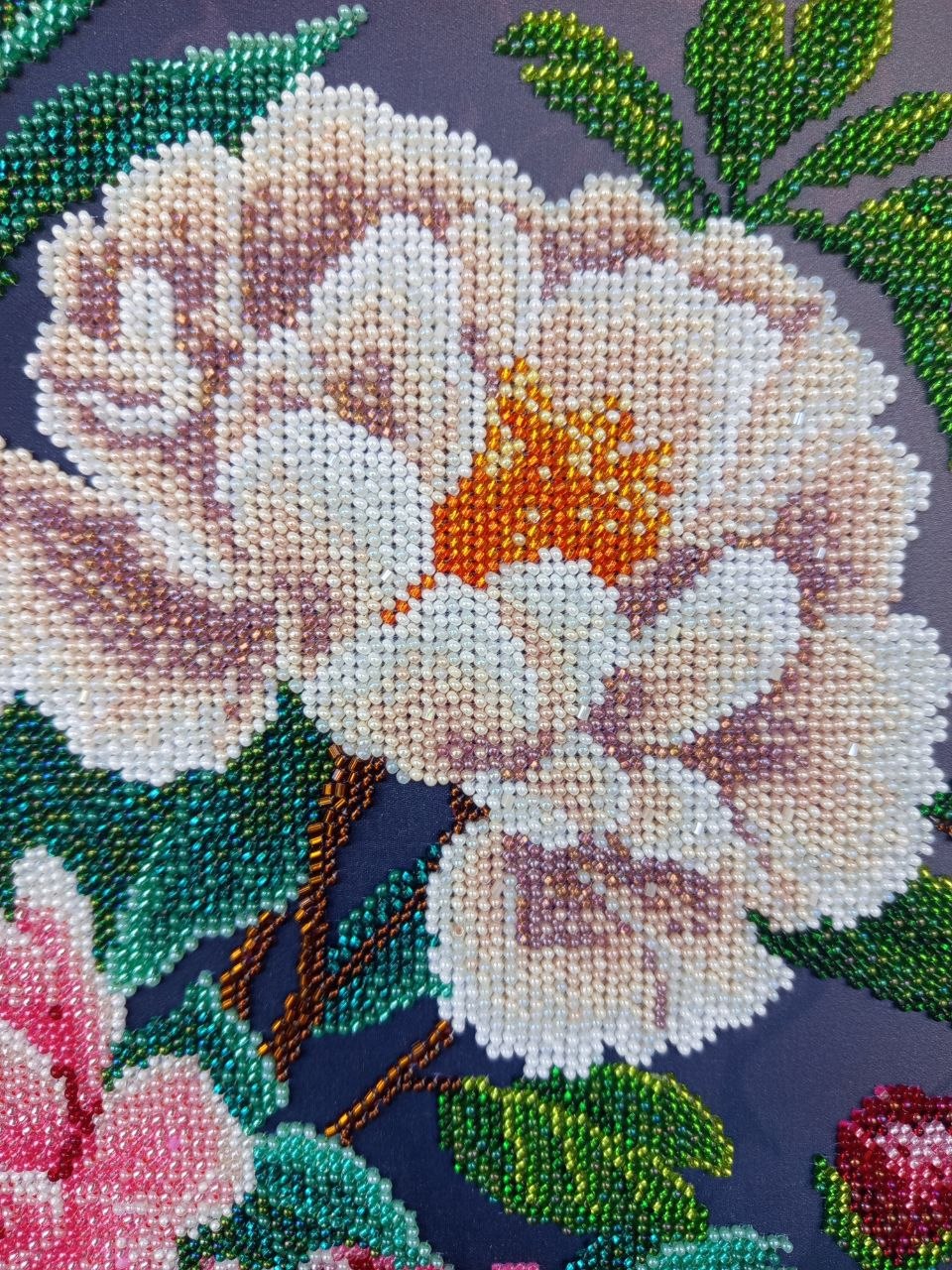 Macro detail of a white peony embroidered with glass beads in shades of ivory, blush and soft lavender